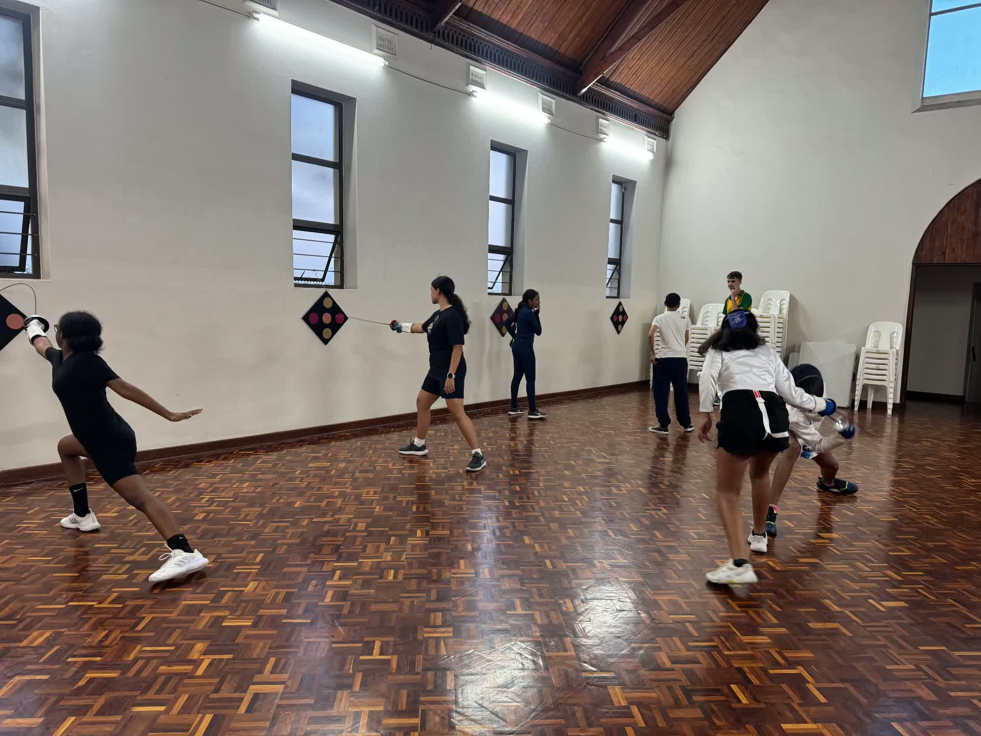 Young fencers training together in a club hall in Durban