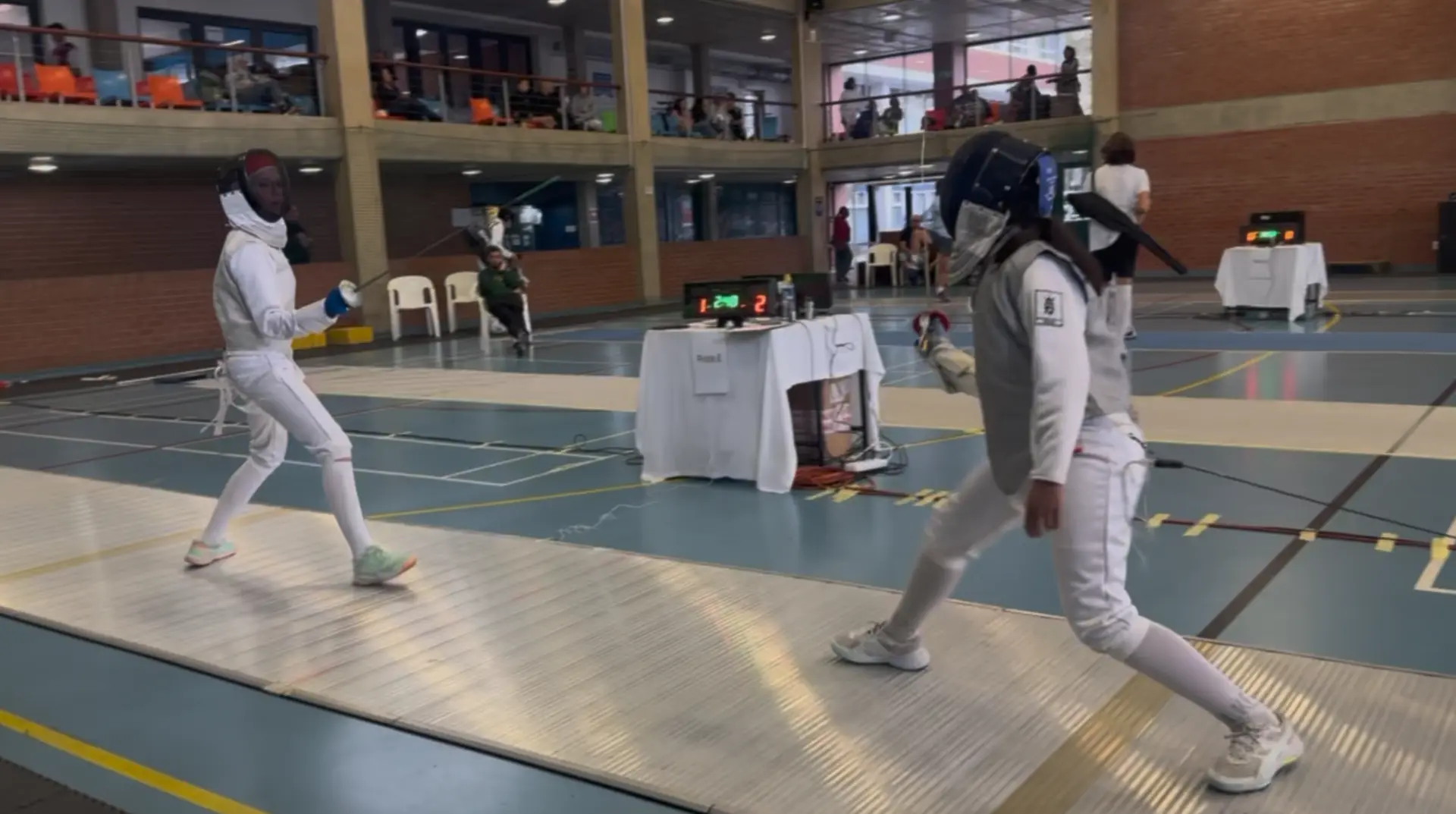 Two young fencers bouting on the piste during a school fencing competition in KwaZulu-Natal