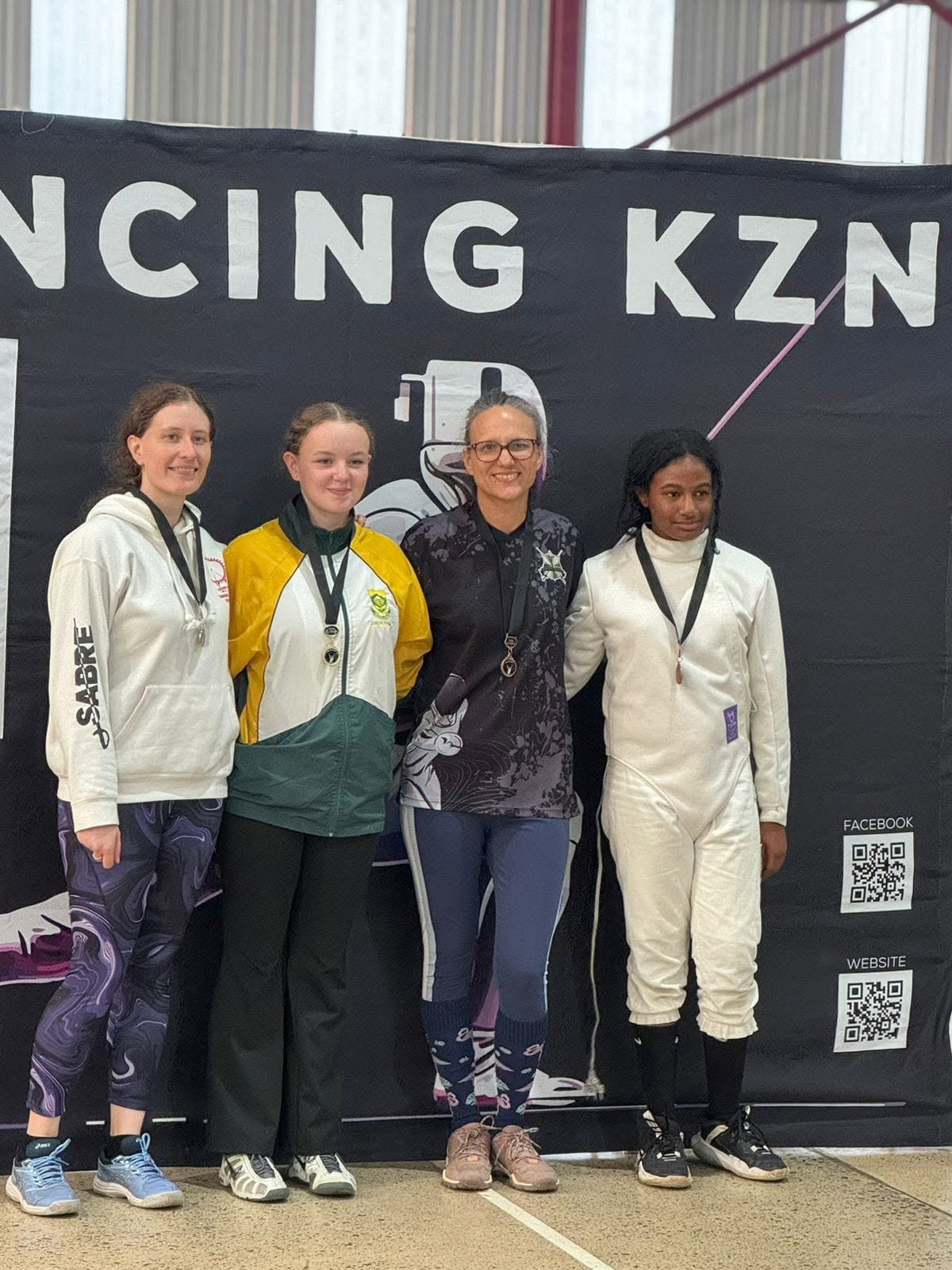 Four fencers with medals standing in front of the Fencing KZN banner