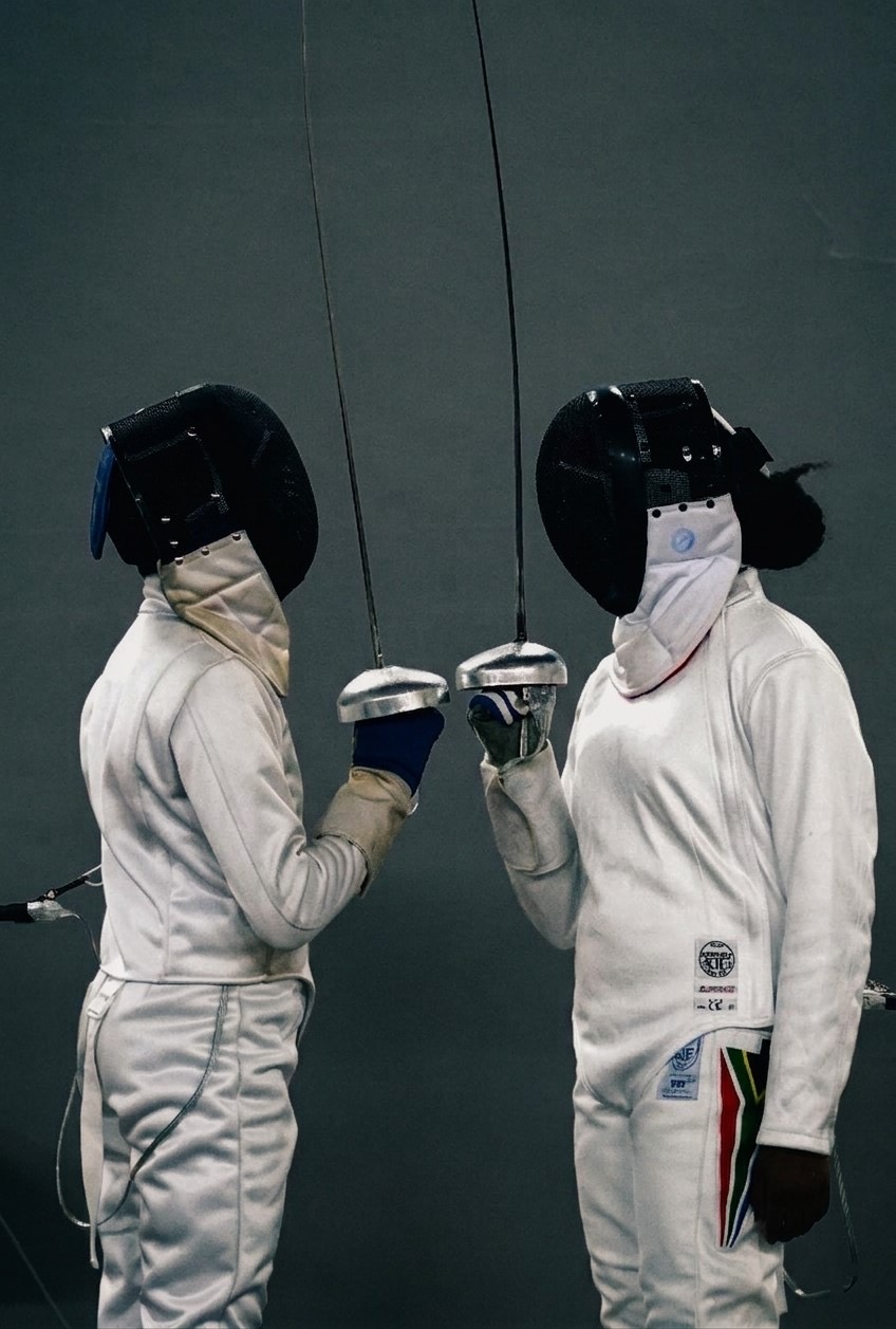 Two fencers in white kit facing each other and saluting before a bout