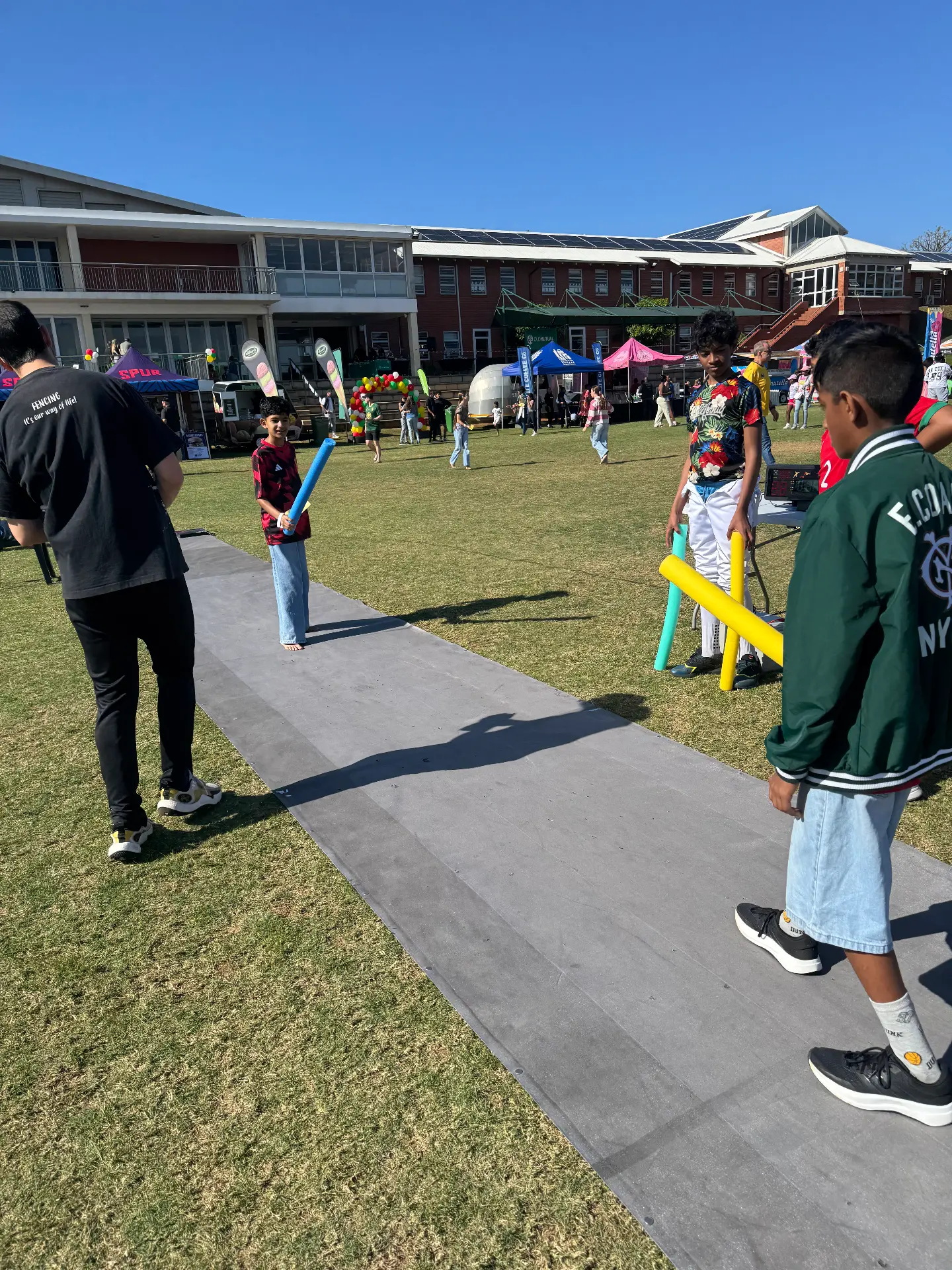 Children trying fencing with foam training swords on the piste at the Reddam House Umhlanga Carnival