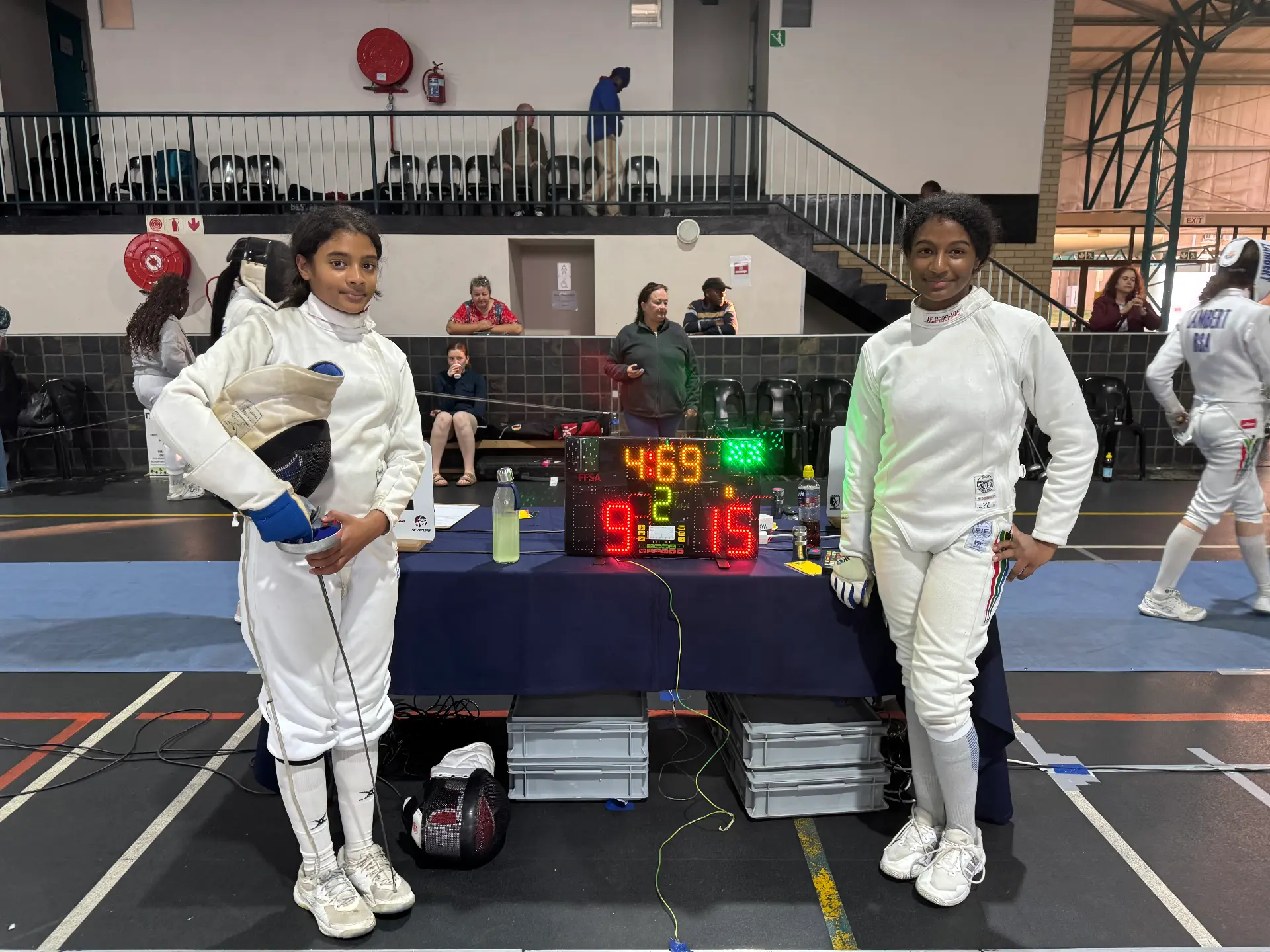 Two KZN fencers beside the FFSA scoreboard after their Free State Open bout